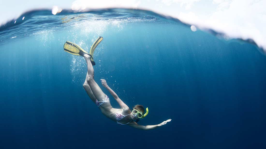 A woman swimming underwater with flippers and mask.
