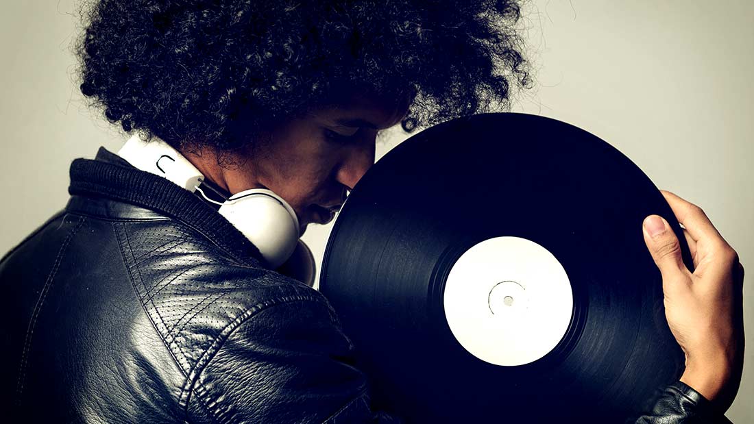 A man with headphones holding up a record.