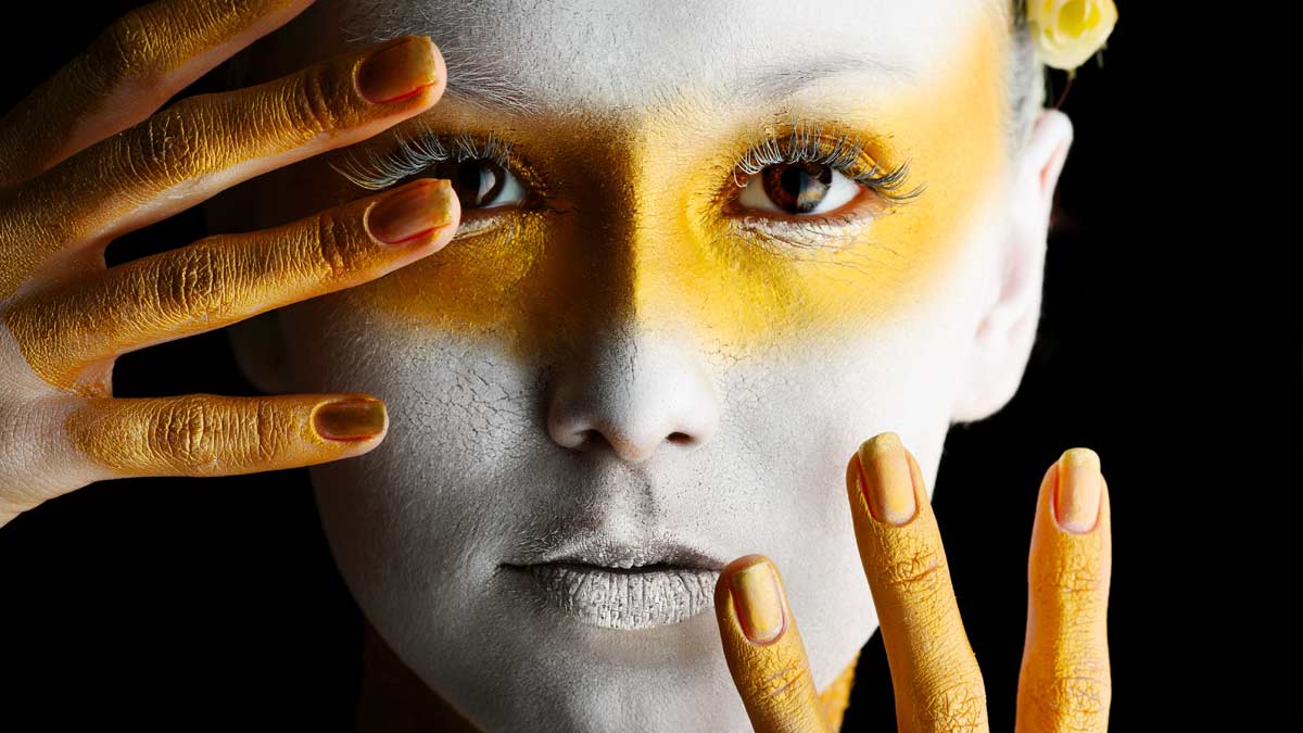 A woman with yellow makeup on her face and hands